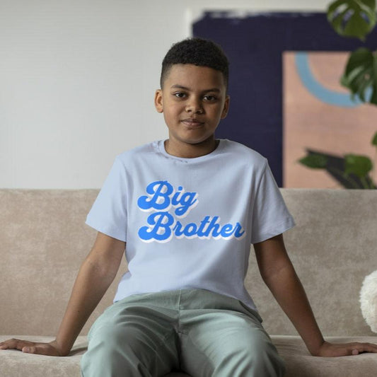 A boy sitting on a couch wearing a blue  variation of the Big Brother tshirt